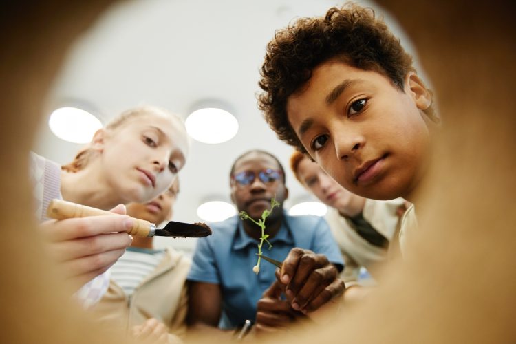 Low angle view of kids looking inside while doing experiments in class